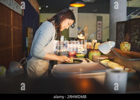 Sushi-Koch, Restaurant und Zubereitung in der Küche mit Start, Service oder Teller auf dem Tisch, Job oder Catering. Kleine Unternehmen, Fast Food und Kochen im Café Stockfoto
