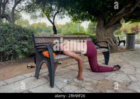 Betrunkener Mann schläft auf einer Bank in Gan HaAtsmaut oder im Independence Park, einem Stadtpark in West-Jerusalem, Israel Stockfoto