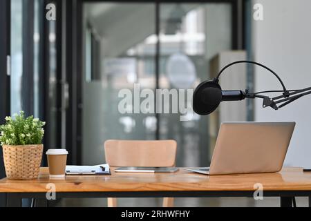 Studio-Podcast-Innenraum mit professionellem Kondensatormikrofon und Laptop auf Holztisch. Technologie und Audiogeräte Stockfoto