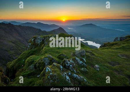 Snowdonia. Der Sonnenaufgang vom Gipfel des Mount Snowdon, Yr Wyddfa, mit Blick nach Osten in Richtung Glaslyn See (nächste Kamera) und Llyn Llydaw dahinter. Schnee Stockfoto