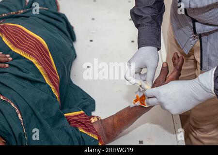 Ein Arzt in einem weißen Fell bindet vorsichtig die gebrochene Hand einer älteren Frau Stockfoto