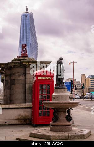 Vertical photo of 1 One Blackriars office building with a red classic telephone booth in fron and the Blackfriars Bridge in London, United Kingdom Stock Photo