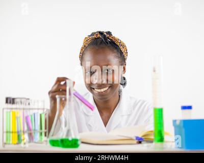 Junge Wissenschaftlerin, die eine Probe in einem Reagenzglas in einem Labor hält. Blick auf die Kamera Stockfoto