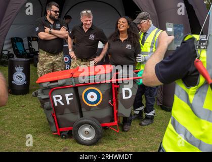 Eastbourne, Großbritannien. August 2023. Ein älterer Stadtbewohner mit seinen in den militärischen Camoflage-Farben bemalten Mülleimern und einem RAF-Rundbogen posiert für ein Foto mit Teammitgliedern des RAF Battle of Britain Memorial Flight in der Militärausstellung neben der jährlichen Eastbourne Airbourne, einer internationalen Flugschau. Die Show findet vier Tage lang statt, mit Flugvorführungen entlang der Küste. Andy Soloman/Alamy Live News Stockfoto