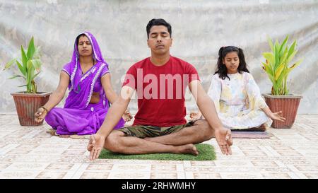 indische Familie, die auf dem Boden meditiert. Gute Lebensgewohnheit, gesunder Lebensstil, Yoga-Praxis mit Kindern zu Hause Stockfoto