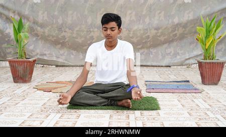 Yoga für Kinder. Der kleine Junge macht Sport. Kaukasischer Junge in einem weißen T-Shirt, der Yoga macht, isoliert über dem Studiohintergrund. Stockfoto