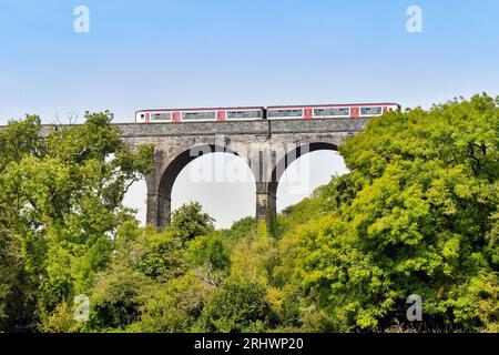 Barry, Wales – 17. August 2023: Pendlerzug von Transport for Wales, der das Steinviadukt über Porthkerry Country Psrk in Südwales überquert Stockfoto