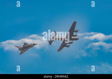 Eastbourne, Großbritannien. August 2023. Ein moderner RAF-Kampfflugzeug vom Typ Typhoon und ein Lancaster-Bomber aus der zweiten Weltkrieg-Ära fliegen an der Küste vorbei auf der jährlichen Eastbourne Airbourne, einer internationalen Flugshow. Die Show findet vier Tage lang statt, mit Flugvorführungen entlang der Küste. Andy Soloman/Alamy Live News Stockfoto