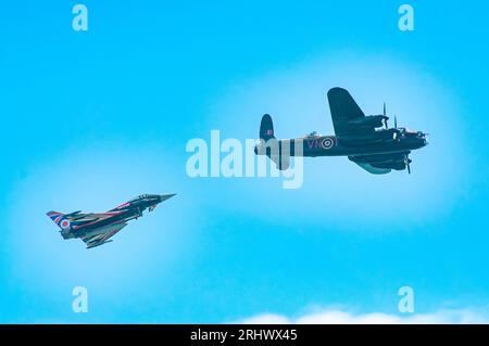 Eastbourne, Großbritannien. August 2023. Ein moderner RAF-Kampfflugzeug vom Typ Typhoon und ein Lancaster-Bomber aus der zweiten Weltkrieg-Ära fliegen an der Küste vorbei auf der jährlichen Eastbourne Airbourne, einer internationalen Flugshow. Die Show findet vier Tage lang statt, mit Flugvorführungen entlang der Küste. Andy Soloman/Alamy Live News Stockfoto