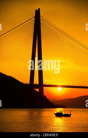 Silhouette bei Sonnenuntergang der Yavuz Sultan Selim Brücke und Fischerboot in Istanbul Türkei Stockfoto