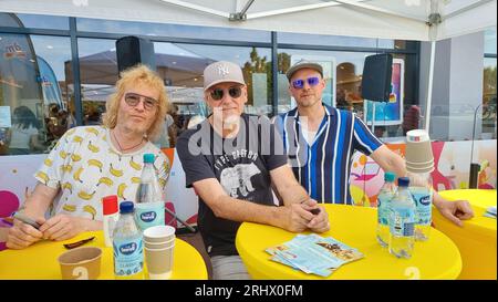 Hannover, Deutschland. August 2023. Christof Stein-Schneider (l-r), Gitarrist, Kai Wingenfelder, Sänger und Christian Decker, Bassist von der Band „Fury in the Smetzhouse“ signiert Autogramme vor dem Zweig einer Drogeriekette. Die sechs Mitglieder der Band "Fury im Schlachthof" sitzen für eine Stunde an der Kasse einer Drogerie für einen guten Zweck. Die Drogerie spendet den gesamten Erlös für die jährliche Weihnachtsfeier für Obdachlose und Bedürftige in Hannover. Quelle: Fernando Martinez/TNN/dpa/Alamy Live News Stockfoto