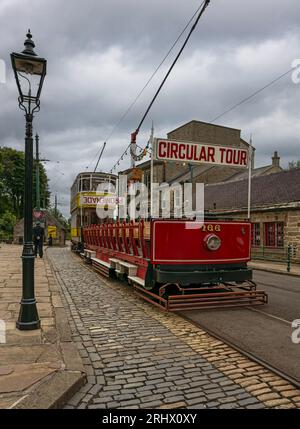 Eine 1927 Blackpool 'Toast-Rack' offene Straßenbahn (Nummer 166) fotografiert an der Haltestelle Stephenson Place Tram am Crich Tramway Village. Stockfoto