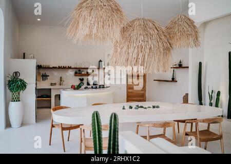 Luxuriöses Innendesign im Wohnzimmer mit offener Küche. Luftiger und heller Raum mit hoher Decke und Steinesstisch Stockfoto