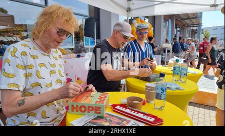 Hannover, Deutschland. August 2023. Christof Stein-Schneider (l-r), Gitarrist, Kai Wingenfelder, Sänger und Christian Decker, Bassist von der Band „Fury in the Smetzhouse“ signiert Autogramme vor dem Zweig einer Drogeriekette. Die sechs Mitglieder der Band "Fury im Schlachthof" sitzen für eine Stunde an der Kasse einer Drogerie für einen guten Zweck. Die Drogerie spendet den gesamten Erlös für die jährliche Weihnachtsfeier für Obdachlose und Bedürftige in Hannover. Quelle: Fernando Martinez/TNN/dpa/Alamy Live News Stockfoto