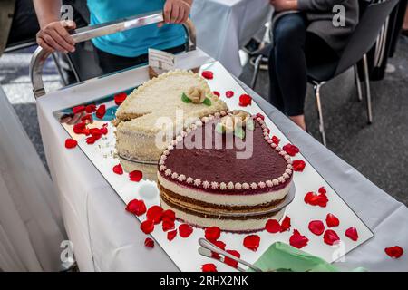 Romantische Hochzeit zwei Kuchen in Herzform, Rosenstrauß auf weißem Tischhintergrund. Draufsicht. Stockfoto