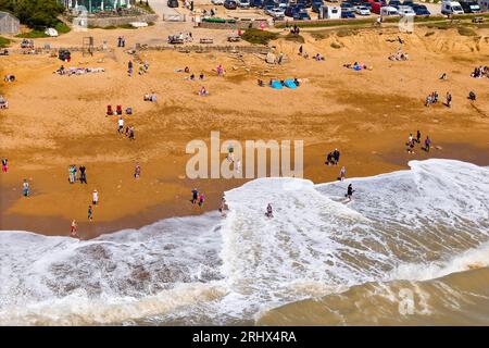Burton Bradstock, Dorset, Großbritannien. August 2023. Wetter in Großbritannien. Raue Meere von Storm Betty stürzen an Land bis zum Hive Beach in Burton Bradstock an der Dorset Jurassic Coast, während Urlauber die glühend heiße Nachmittagssonne genießen. Bildnachweis: Graham Hunt/Alamy Live News Stockfoto