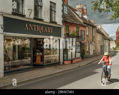 Ein Radfahrer fährt entlang der Abbey Row gegenüber der historischen Abtei in der Marktgemeinde Wiltshire von Malmesbury. Stockfoto