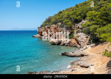 Griechenland, Dragonera Strand auf der Insel Agistri am Saronischen Golf. Felsige Landschaft mit Kiefern bedeckt, kristallklares Meer, blauer Himmel, Sommerziel. Stockfoto