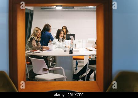 Die Kollegen teilten sich in zwei Drittel auf, die im Büro ein Projekt diskutierten und daran arbeiteten Stockfoto