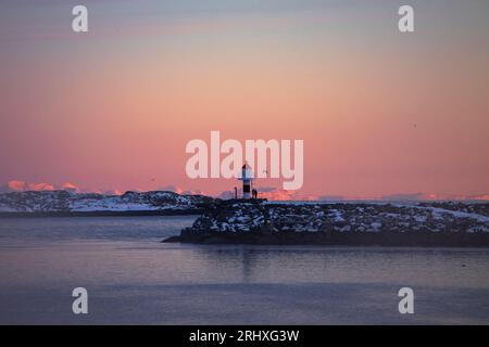 Fantastische Aussicht auf das Leuchtturm, das sich am Ufer des ruhigen Meeres vor dem wolkenlosen Sonnenuntergang auf den Lofoten-Inseln in Norwegen befindet Stockfoto