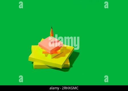 Hoher Winkel des kleinen Bleistiftes auf einem Stapel gelber und rosa Haftnotizen auf hellgrünem Hintergrund, der das Konzept des Schulbeginns darstellt Stockfoto