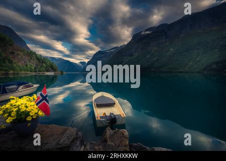 Norwegischer Bergsee mit Boot, Wolken und atemberaubenden Reflexen der Natur. Stockfoto
