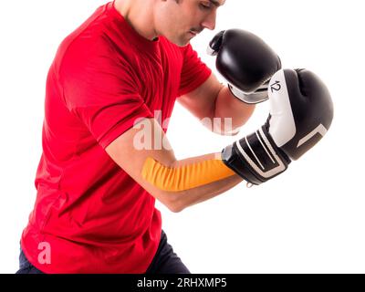 Foto eines Mannes mit rotem Hemd und schwarz-weißen Boxhandschuhen in einem Studio Stockfoto