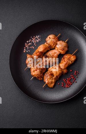 Köstlich frisches, saftiges Hühnchen oder Schweinekeback auf Spießen mit Salz und Gewürzen auf dunklem Betonhintergrund Stockfoto