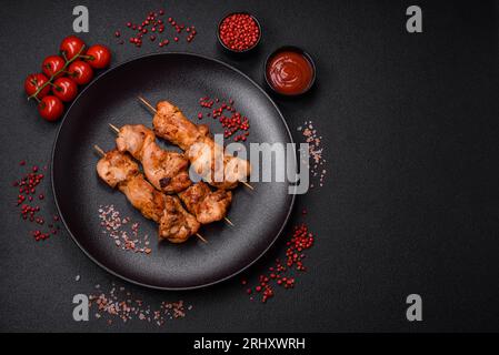 Köstlich frisches, saftiges Hühnchen oder Schweinekeback auf Spießen mit Salz und Gewürzen auf dunklem Betonhintergrund Stockfoto