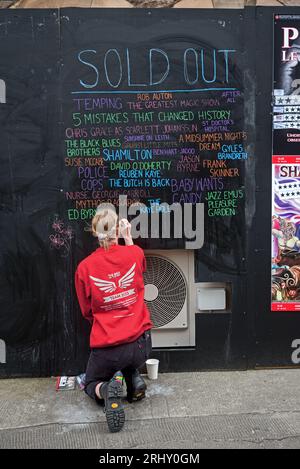 Eine junge Frau aus der Versammlung, die die ausverkaufte Tafel aktualisiert. Edinburgh Fringe 2023. Stockfoto