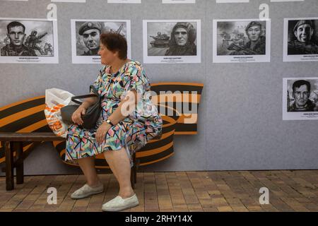 Moskau, Russland. August 2023. Eine Frau sitzt vor dem Hintergrund des Ausstellungsprojekts „Heroes of z.O.V.“, das russischen Soldaten gewidmet ist, die an einer speziellen Militäroperation teilnehmen, am Ort des XII. Interregionalen Festivals für slawische Kunst „Russisches Feld“ auf einem Territorium des Kolomenskoje-Museums-Reservats in Moskau, Russland Stockfoto