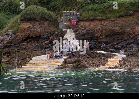 Herm, Kanalinseln. 11. Juni 2023. Die Rosaire Steps, Herm bei Ebbe von einer sich nähernden Passagierfähre gesehen. Passagiere warten an Land. Stockfoto