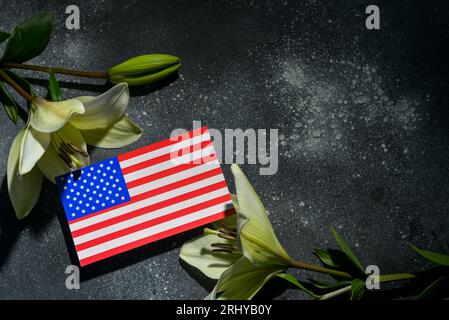 USA-Flagge mit Lilien auf schwarzem Hintergrund. Nationaler Tag des Gebets und der Erinnerung an die Opfer der Terroranschläge Stockfoto