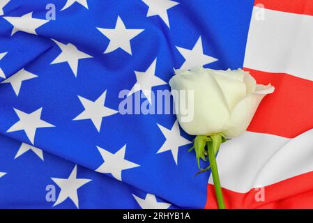 Rose Blume auf der Flagge der USA als Hintergrund. Nationaler Tag des Gebets und der Erinnerung an die Opfer der Terroranschläge Stockfoto