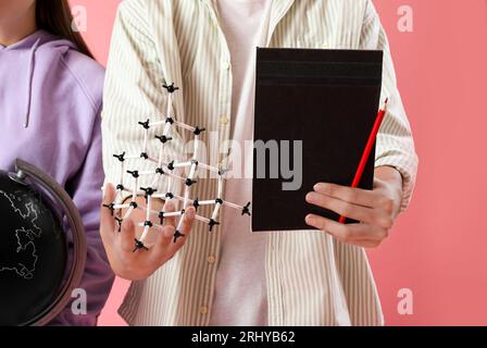 Studenten mit Globus, Molekularmodell und Notizbuch auf rosafarbenem Hintergrund Stockfoto