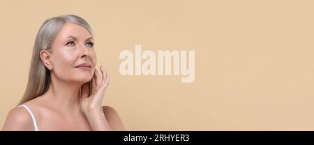 Porträt einer schönen Reifen Frau auf beigem Hintergrund. Bannerdesign mit Platz für Text Stockfoto