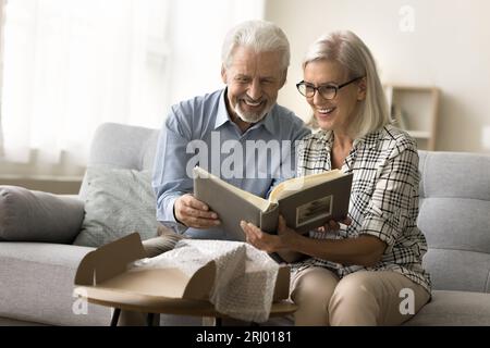 Ein fröhliches älteres Paar, das verliebt ist, ein Paket zu öffnen, eine Pappschachtel Stockfoto