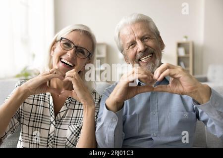Ein fröhliches, verliebtes Paar zeigt herzförmige Hände Stockfoto