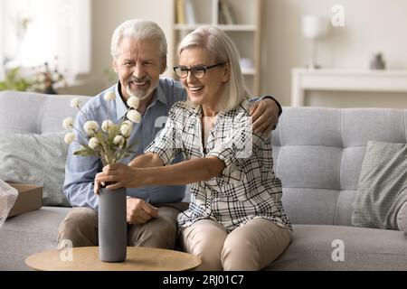 Glückliche ältere Frau, die ein paar Blumen von einem liebevollen Ehemann bekam Stockfoto