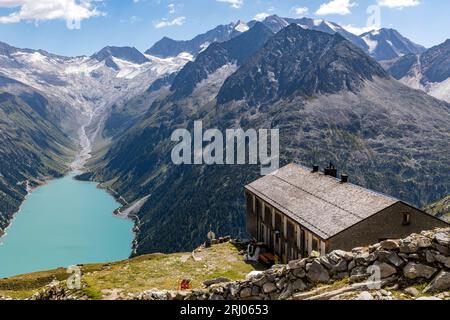 Österreich. August 2023. Über dem 1782 Meter hohen Stausee Schlegeis auf einem Wanderweg in den Zillertaler Alpen liegt die Olpererhütte auf 2389 Metern. Der Stausee ist einer von fünf Stauseen im Zillertal und hat eine Fläche von etwa 220 Hektar. Sie ist Ausgangspunkt für eine Vielzahl beliebter Wanderungen - wie diese zur Olpererhütte. Quelle: Frank Hammerschmidt/dpa/Alamy Live News Stockfoto