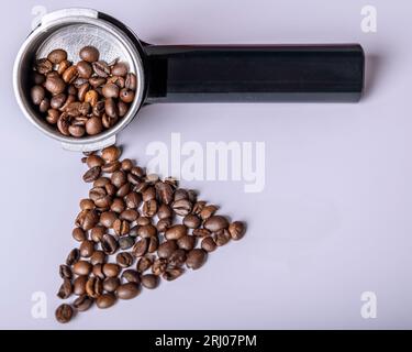 Die Kaffeebohnen befinden sich in einem Auslegerarm für die Kaffeemaschine und auf einem weißen Tisch Stockfoto