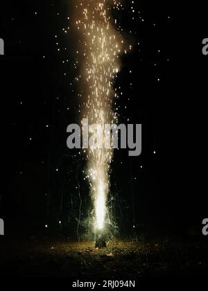 Ein Funken- und Rauchbrunnen, der nachts während eines Festivals aus einem diwali-Blumenkegel-Feuerkracher platzt Stockfoto