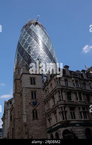 London, Großbritannien. August 2023. Das zeitgenössische Gherkin-Gebäude in der City of London. Wikapedia führt es als „30 St Mary Axe und früher bekannt als Swiss Re Building, ist ein kommerzieller Wolkenkratzer in Londons wichtigstem Finanzviertel, der City of London. Sie wurde im Dezember 2003 fertiggestellt und im April 2004 eröffnet. Mit 41 Etagen ist er 180 Meter (591 ft) hoch und steht an den Standorten der ehemaligen Ostseebörse und der Schifffahrtskammer. die 1992 beim Bombenanschlag auf die Baltische Börse durch eine Vorrichtung der Provisorischen IRA in St. Mary Axe, einer schmalen Straße, schwer beschädigt wurden Stockfoto