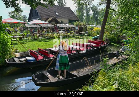 Burg, Deutschland. August 2023. Eine Frau in sorbisch-wenisch-traditioneller Tracht reist auf einem Holzkahn auf einem Fluss (Wasserstraße) im Spreewald. Quelle: Patrick Pleul/dpa/Alamy Live News Stockfoto