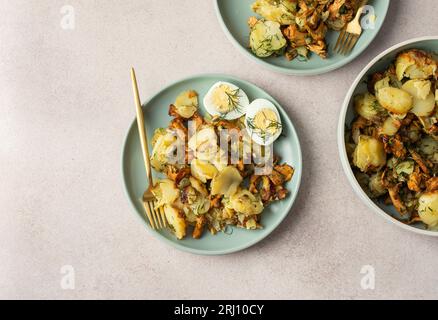 Köstliche herzhafte Abendessen oder Mittagessen, gebratene junge Kartoffeln mit Waldpilzen Chanterelles mit Dill, gekochte Eier, saisonale Speisen Stockfoto