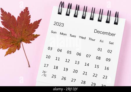 Dezember 2023 Schreibtischkalender für 2023 Jahre mit Herbstahornblatt auf rosafarbenem Hintergrund. Stockfoto