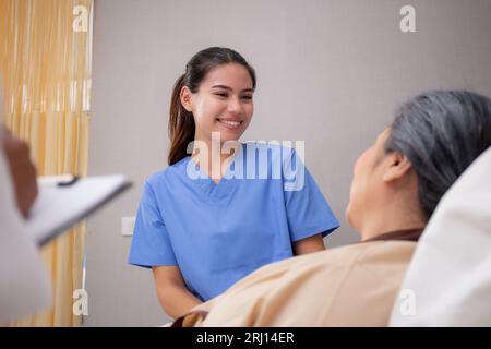 Junge Pflegekraft oder Krankenschwester Pflege und sprechender Patient ältere auf dem Bett zum Trosten im Zimmer auf der Krankenhausstation, Arzt Untersuchung und Diagnose mit Senior W Stockfoto