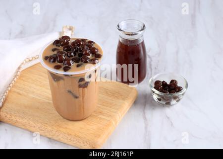 Boba Milk Tea in Plastic Takeaway Cup, auf weißem Tisch Stockfoto