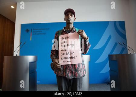 Berlin, Deutschland. August 2023. Ein Aktivist im Innenministerium trägt am 20. August 2023 ein Schild mit der Aufschrift „es gibt keine Fluechtlingskrise, das ist die Klimakrise“. Quelle: ZUMA Press, Inc./Alamy Live News Stockfoto