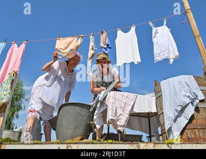 Burg, Deutschland. August 2023. Zwei Frauen zeigen, wie Wäsche vor 100 Jahren gewaschen wurde, auf dem Festzug in der Spreewaldstadt Burg. Am Nachmittag fand die große Parade zum 29. Heimat- und Trachtenfest im Spreewald statt. Quelle: Patrick Pleul/dpa/Alamy Live News Stockfoto